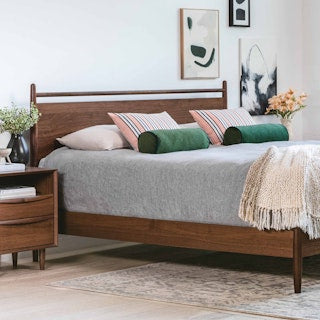  TheLegacyPanelBed Wooden bed with gray bedding and decorative pillows in a bedroom setting.