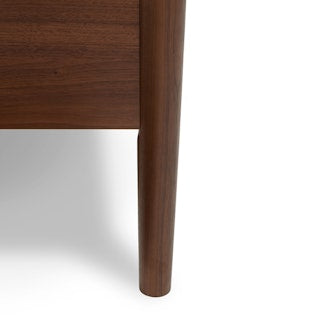 "Close-up of the bed's panel headboard, highlighting the natural grain and rich texture of the walnut wood finish."