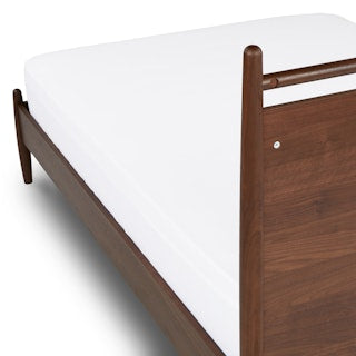 TheLegacyPanelBed Wooden bed frame with a white mattress on a white background